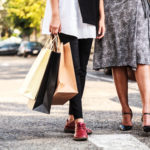 Female Ladies carrying Colorful Shopping Bags in the parking lots Concept.